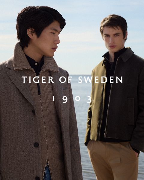 Deux hommes en manteaux élégants se tiennent à l'extérieur au bord de l'eau sous un ciel clair. Le texte « TIGER OF SWEDEN 1903 » est centré sur l'image.