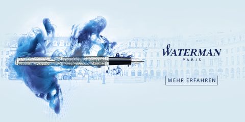 Un luxueux stylo plume argenté orné de motifs complexes est entouré de volutes d'encre bleue. L'arrière-plan présente un paysage urbain élégant. Le logo "Waterman Paris" et le texte "En savoir plus" sont visibles.