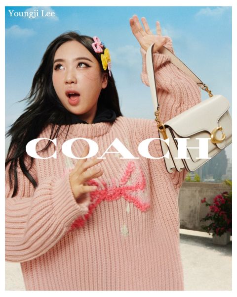 Une personne tient un sac à main blanc et porte un pull en tricot rose et un accessoire pour cheveux. En arrière-plan, on peut voir un ciel bleu et un paysage de toits. Le texte sur l'image est « Youngji Lee » et « Coach ».