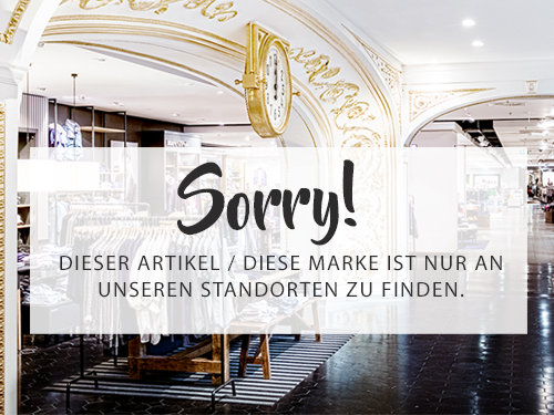 Intérieur d'un magasin élégant avec un décor vintage et une grande horloge. Un message au premier plan indique : « Désolé ! Cet article / Cette marque n'est disponible que dans nos magasins », soulignant l'exclusivité de la disponibilité en magasin.