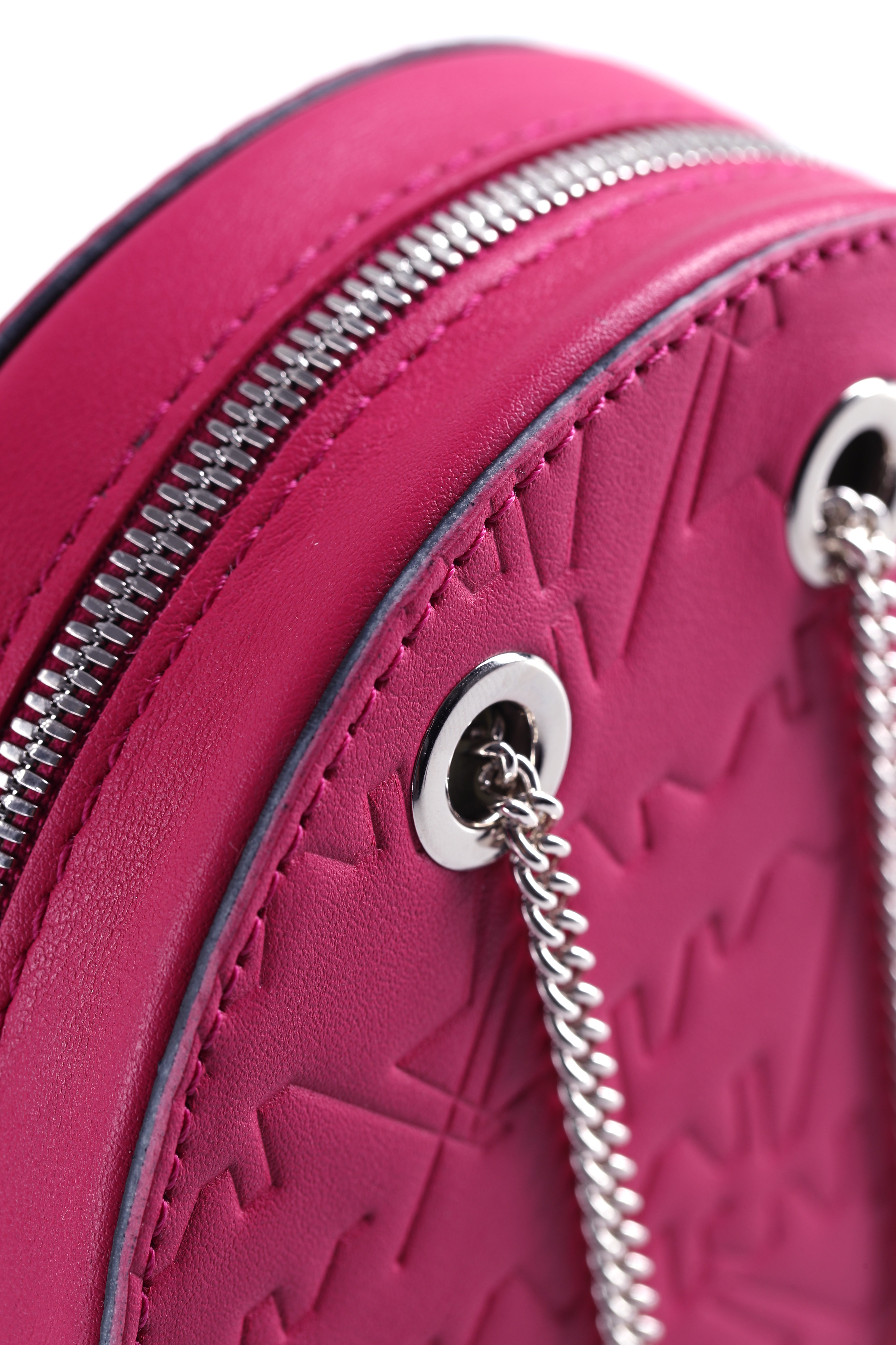 Nahaufnahme einer runden rosa Handtasche mit silbernen Kettenriemen und geprägten Mustern. Die Handtasche verfügt über silberne Reißverschlüsse und Ösen.