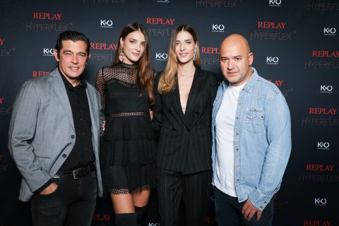 Quatre personnes sourient devant un fond avec les logos « Replay Hyperflex » et « KO ». Les deux femmes au milieu portent des tenues noires élégantes, tandis que les hommes de chaque côté portent des vêtements décontractés.