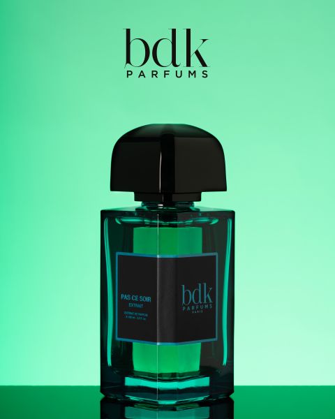 Un flacon d'extrait "Pas Ce Soir" de BDK Parfums, avec un élégant bouchon noir, est présenté devant un fond vert dégradé. Le logo de BDK Parfums est visible en haut de l'image.