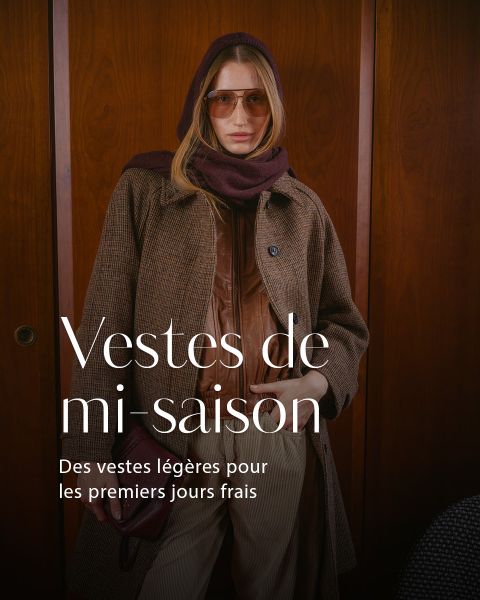 Une femme en manteau marron, avec une écharpe et des lunettes de soleil, se tient devant des panneaux en bois. Au-dessus, un texte français sur les vestes légères pour les journées fraîches est affiché.