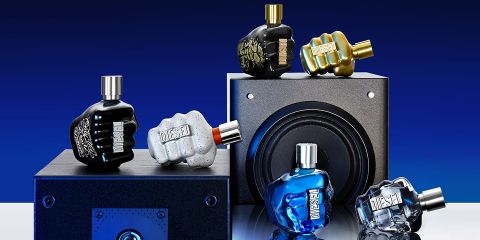 Divers flacons de parfum en forme de poings serrés sont présentés sur et autour d'un haut-parleur noir devant un fond bleu dégradé. Les flacons sont disponibles en différentes couleurs, notamment noir, or, gris, bleu et transparent.