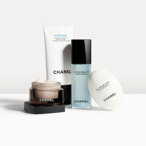 Quatre produits de soin de la peau Chanel sont disposés devant un fond clair : une mousse nettoyante, un micro-sérum, une crème hydratante et une crème pour les mains, chacun dans un emballage individuel avec le logo de la marque visible.