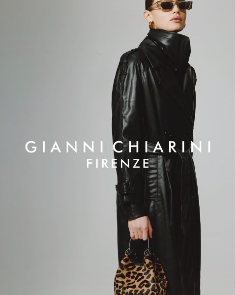 Personne portant un long trench-coat noir en cuir et des lunettes de soleil, tenant un petit sac à motif léopard. Le fond est gris, avec le texte "GIANNI CHIARINI FIRENZE" en blanc au-dessus de l'image.
