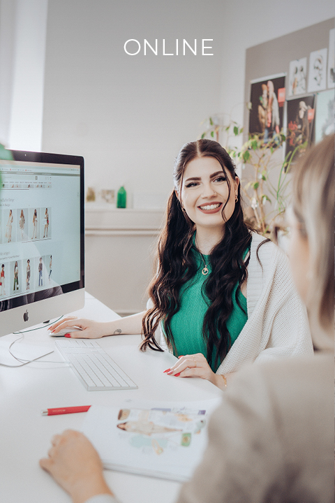 Une femme aux longs cheveux foncés, portant un haut vert et un cardigan blanc, sourit en travaillant sur un ordinateur. L'écran affiche des images. Au premier plan, on aperçoit une autre personne, floue. Le texte en haut indique « EN LIGNE ».