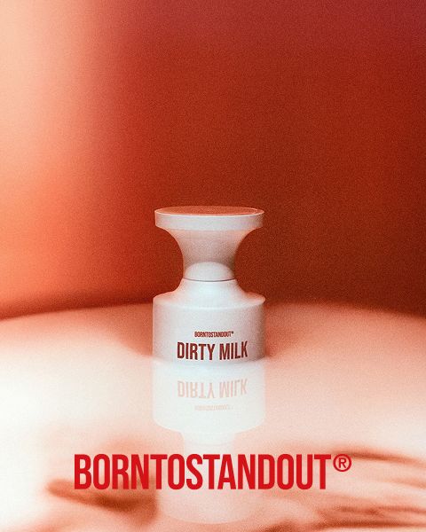 Une bouteille blanche portant l'inscription "DIRTY MILK" repose sur une surface réfléchissante avec un dégradé rouge chaud. En dessous, en gras rouge, on peut lire "BORNTOSTANDOUT®".