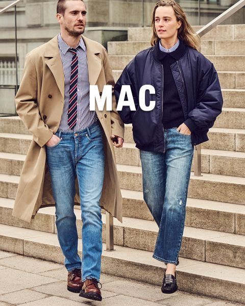 Un homme en trench-coat et une femme en veste bleu marine descendent un escalier en pierre en jean. Au-dessus de l'image, on peut voir l'inscription "MAC".