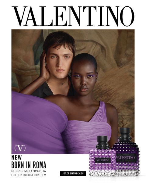 Un homme et une femme posent ensemble sur des marches en pierre. L'homme porte un manteau noir, la femme une tenue rose vif à épaules dénudées. En bas à droite, on voit deux flacons de parfum Valentino. Au-dessus, il est écrit « VALENTINO ».