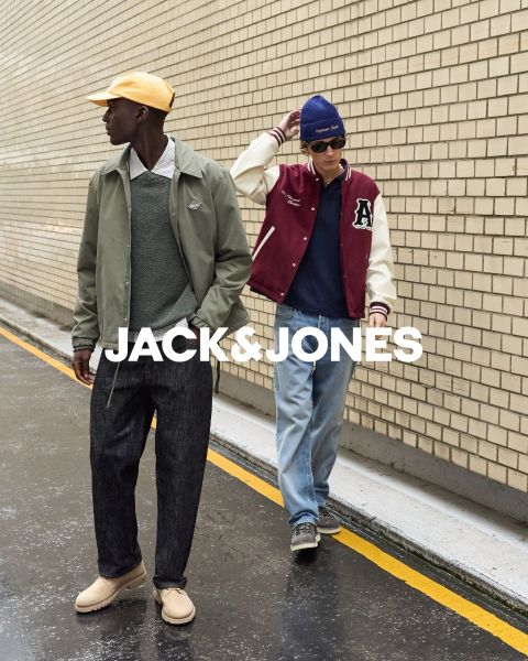 Deux hommes en tenue de jeans sont assis devant un fond simple. L'homme de devant porte sa main à sa bouche, tandis que l'autre est assis derrière lui. Au centre, on peut lire le texte "JACK & JONES".