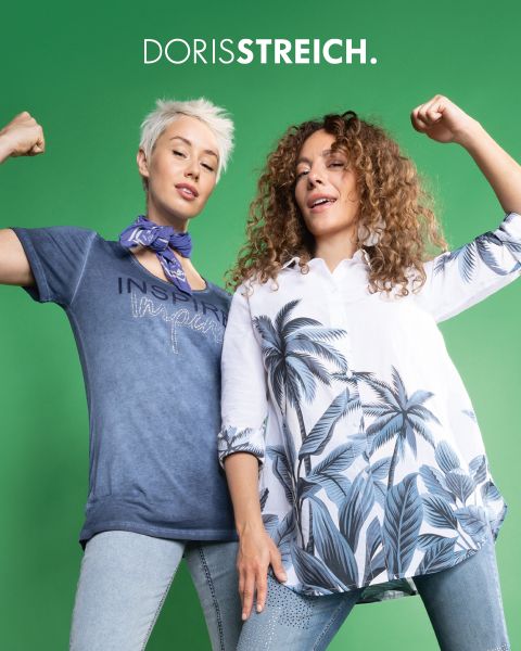 Deux femmes posent avec assurance dans des tenues noires et blanches avec des accents verts, notamment un gilet matelassé, un bonnet et des chaussures, devant un fond sombre avec le texte "DORIS STREICH" au-dessus d'elles.