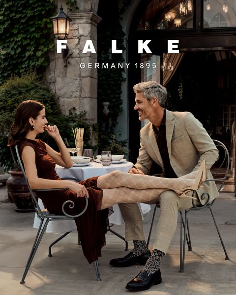 Un mannequin portant un blazer marron, des gants marron, des collants verts, une jupe grise à fentes hautes et des bottines marron pose devant un fond géométrique. Le texte indique "FALKE ALLEMAGNE 1895".