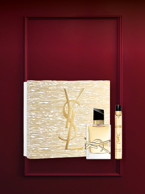 Coffret cadeau de parfum dans un cadre rouge foncé avec une boîte à motifs floraux, un petit flacon de parfum et un tube blanc avec un bouchon doré. En haut, il est écrit « Coffrets de parfums » en blanc.