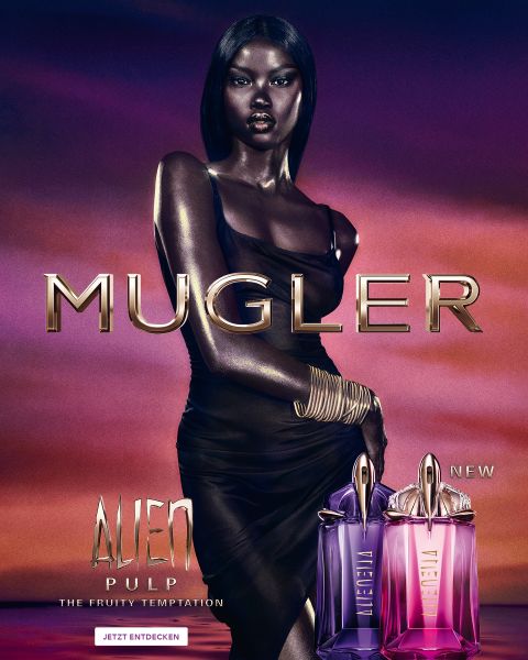 Une femme à la peau foncée et éclatante et aux cheveux noirs lisses pose devant un fond violet. Devant elle se trouvent deux flacons de parfum Alien de Mugler. Le texte indique « MUGLER » et « ALIEN EXTRA INTENSE LES FRAGRANCES RECHARGEABLES ».