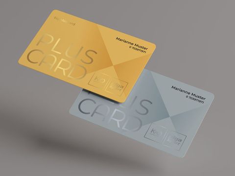 Deux cartes transparentes flottent devant un fond gris. L'une est dorée avec le texte "PLUS CARD", l'autre est bleu clair avec le même design. Les deux portent le nom de "Marianne Muster" et des chiffres en dessous.