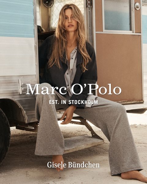 Une femme portant une chemise à carreaux, un short noir et des bottes marron se tient devant un mur en bois patiné. Le texte est le suivant : "Marc O'Polo EST. IN STOCKHOLM Gisele Bündchen.