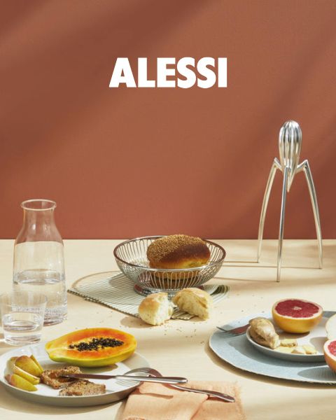Deux coquetiers géométriques modernes avec des œufs sont posés sur un plateau réfléchissant, ainsi qu'un bol en verre et une cuillère. Au bas du centre de l'image, on peut lire « ALESSI » en gras.