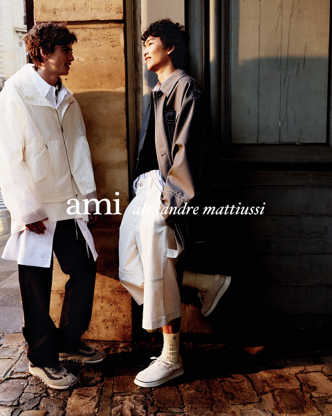 Trois personnes proches les unes des autres, portant des tenues élégantes, l'une tenant une boisson à la main. Le texte "ami alexandre mattiussi" est superposé à l'image en lettres blanches. On ne voit pas leurs visages.