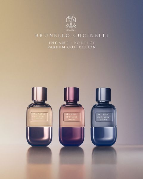 Six flacons de parfum Brunello Cucinelli sont alignés au-dessus d'un lit de fleurs colorées et de verdure. Le texte au-dessus indique « Brunello Cucinelli » et en dessous : « Incanti Poetici Parfum Collection ».