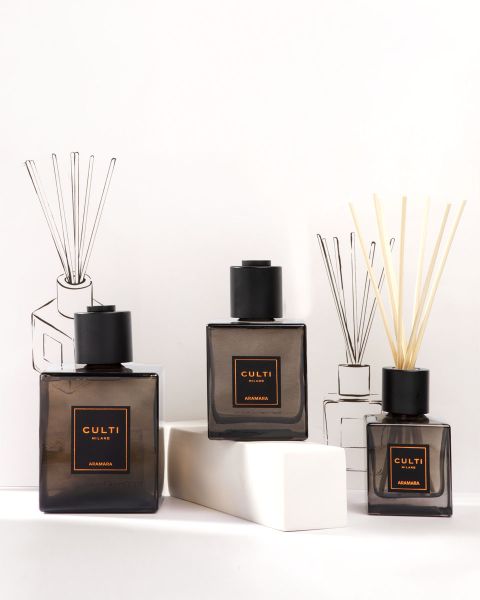 Une présentation élégante des produits de parfums d'intérieur de Culti Milano, comprenant des bougies, un diffuseur avec bâtonnets et des flacons, le tout dans des récipients vert foncé, sur un fond olive avec le logo de Culti Milano en dessous.