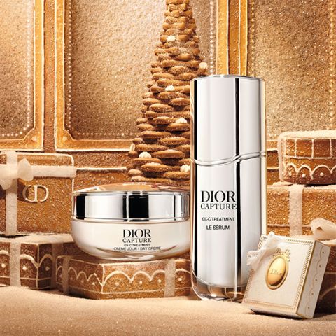 Un tube argenté avec l'inscription « Dior Capture » posé à la verticale sur un fond blanc, son ombre portée vers la droite.