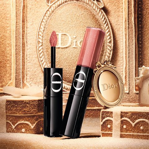 Un rouge à lèvres liquide rouge de Dior, avec son applicateur sorti et son capuchon argenté posé à côté, le tout sur un fond blanc.