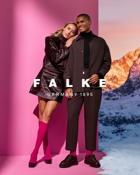 Un mannequin portant un blazer marron, des gants marron, des collants verts, une jupe grise à fentes hautes et des bottines marron pose devant un fond géométrique. Le texte indique "FALKE ALLEMAGNE 1895".