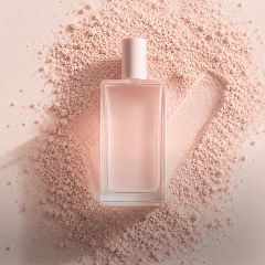 Un flacon de parfum en verre transparent avec un capuchon rose pâle est posé sur de la poudre rose, à côté de laquelle une coche a été tracée dans la poudre.