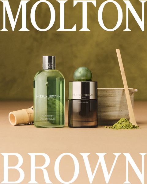 Disposition à plat de divers flacons et récipients Molton Brown sur un fond clair, avec le texte « Molton Brown London, Parfum distinctif, Fabriqué en Angleterre » au centre. Des accents sphériques en verre sont dispersés partout.