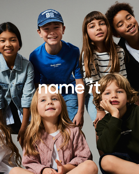 Un groupe de huit enfants différents se tient ensemble devant un fond gris, tous portant des tenues décontractées et assorties dans des tons neutres et pastel. Le texte "name it" apparaît au centre de l'image.
