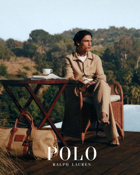 Un homme et une femme portent d'élégants trench-coats Ralph Lauren. L'homme associe son manteau à un pull coloré et un pantalon gris, tandis que la femme porte une chemise rayée, des gants marron et une large ceinture. "POLO RALPH LAUREN" est affiché en lettres blanches.