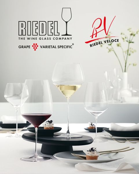 Six verres en cristal colorés avec des motifs taillés complexes sont disposés sur une surface en marbre foncé. Au-dessus, le logo Riedel arbore le nom de la marque et un symbole de verre à vin.