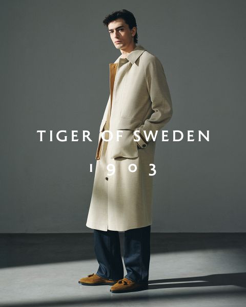 Deux hommes en manteaux élégants se tiennent à l'extérieur au bord de l'eau sous un ciel clair. Le texte « TIGER OF SWEDEN 1903 » est centré sur l'image.