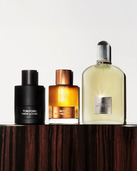 Une photo en noir et blanc montrant un homme et une femme portant des chapeaux à larges bords. Ils se tiennent très près l'un de l'autre. Dans le coin inférieur gauche, il y a une bouteille étiquetée « Tom Ford Eau d'Ombre Leather ». Le nom de la marque est clairement visible.