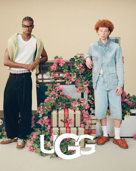 Une paire de bottes UGG en daim marron avec une doublure intérieure moelleuse, posée sur une surface grise. Le logo UGG est bien visible en bas de l'image.