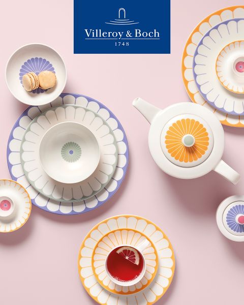 Une exposition de cuisine présente un bol noir avec de petits fouets sur un plateau rectangulaire. À côté, une assiette avec un couvercle en verre expose du fromage et des herbes fraîches. Le logo de Villeroy & Boch trône au sommet.