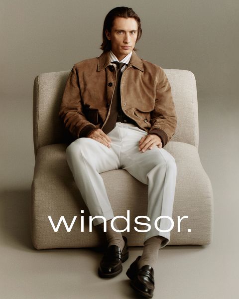 Un homme portant un manteau marron et une femme portant un manteau et une écharpe couleur crème se tiennent à l'extérieur avec des montagnes en arrière-plan. Le mot « windsor. » est visible au bas de l'image.