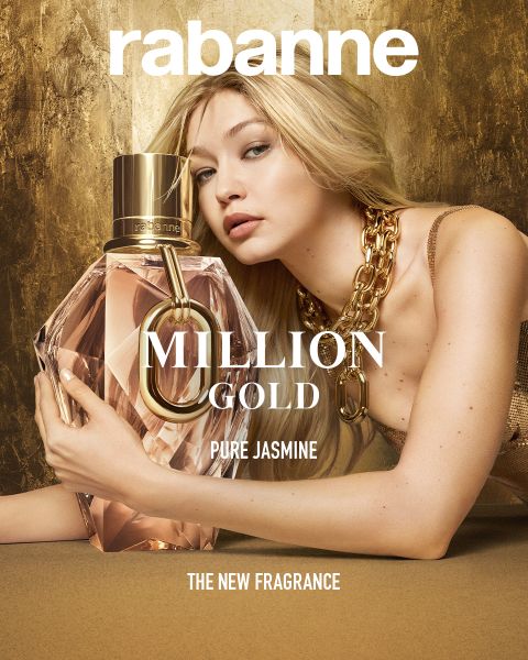 Une femme vêtue d'une robe dorée et d'un collier épais pose avec un grand flacon de parfum à facettes portant l'inscription "Million Gold Pure Jasmine" de Rabanne. L'arrière-plan est doré et, en bas, on peut lire "LE NOUVEAU PARFUM".