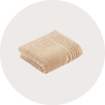 Ein ordentlich gefaltetes beigefarbenes Handtuch mit einem strukturierten Muster und geripptem Rand auf einem hellen, runden Hintergrund.