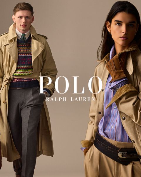 Un homme et une femme portent d'élégants trench-coats Ralph Lauren. L'homme associe son manteau à un pull coloré et un pantalon gris, tandis que la femme porte une chemise rayée, des gants marron et une large ceinture. "POLO RALPH LAUREN" est affiché en lettres blanches.