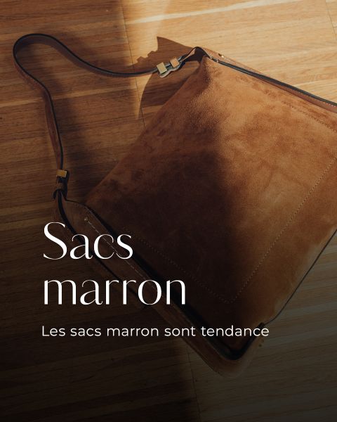 Un sac bandoulière marron en daim avec une bandoulière est posé sur un plancher en bois. Sacs marron. Les sacs marron sont tendance.