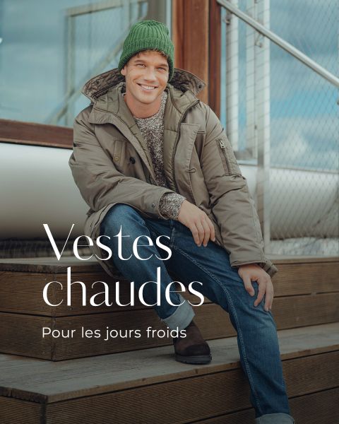 Un homme souriant, portant un bonnet en tricot vert, un manteau d'hiver beige, un pull, un jean et des bottes, est assis sur un escalier en bois à l'extérieur. Le texte français sur l'image est : "Vestes chaudes. Pour les jours froids.