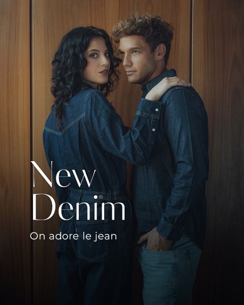 Une femme et un homme en jean foncé se tiennent côte à côte devant un mur en bois. Le texte sur l'image est : "New Denim. On adore le jean."