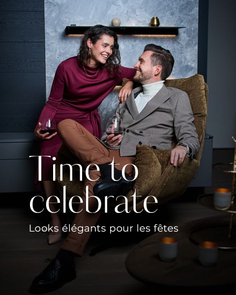 Une femme dans une robe bordeaux et un homme dans un blazer gris et un pantalon marron se sourient en tenant des verres à vin. Le grand texte est "Time to celebrate - Looks élégants pour les fêtes.