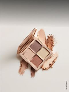 Une palette de fards à paupières ouverte avec quatre teintes neutres, entourée d'échantillons des poudres sur une surface claire.