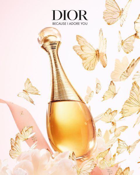 Un flacon de parfum Dior doré, entouré de papillons dorés flottants, d'un ruban rose et de délicates fleurs blanches avec le texte "DIOR Because I Adore You".