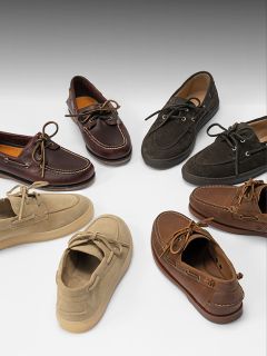 Sept paires de chaussures bateau de différentes couleurs, dont marron, marron clair et noir, disposées en cercle sur un fond blanc.