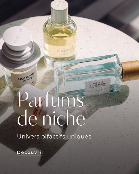 Différents flacons de parfums de niche sur une surface mouchetée avec le texte : « Parfums de niche, Univers olfactifs uniques. Découvrir.